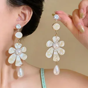 Close-up of elegant flower earrings with pearls and rhinestones on an Asian model