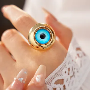 Primo piano di un anello in resina con occhio del diavolo su mano con pizzo.