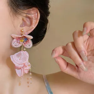 Close-up detail of tiered pink chiffon flower tassel earrings worn on ear