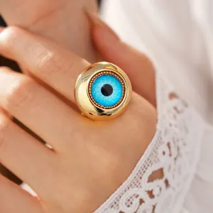 Vista dettagliata di un anello dorato con motivo a occhio di demone in resina blu