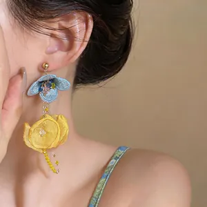 Detail view of large chiffon flower tassel earrings in vibrant blue and yellow colors