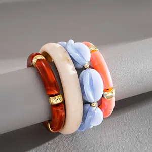 Close-up of four colorful marbled acrylic stretch bracelets with gold-toned metal spacers