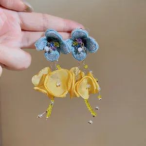 Detailed macro view of handmade embroidered flower earrings with yellow chiffon tassels