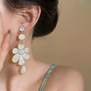 Detail shot of vintage French style flower pearl drop earrings worn by a female model