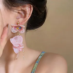 Close-up detail of elegant pink chiffon flower tassel earrings worn by a model