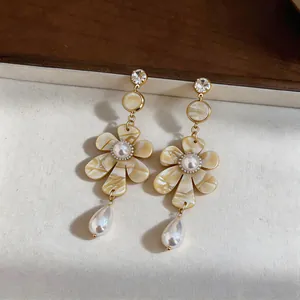 Macro detail of vintage French flower earrings with cream petals and dangling pearls