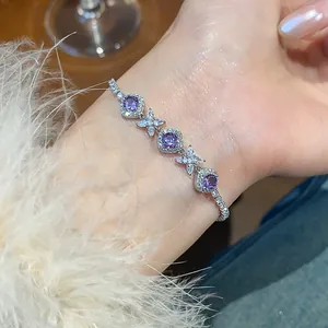 Close-up of a silver zircon bracelet with purple stones and floral accents on a wrist.