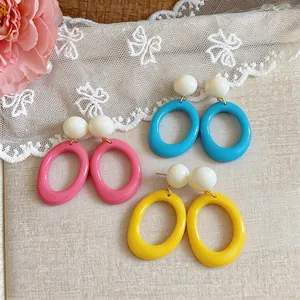 Detail view of colorful dopamine resin oval earrings in pink, blue, and yellow