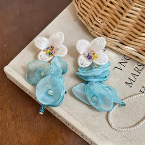 Detailed macro shot of light blue chiffon flower earrings with delicate white lace petals