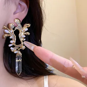 Dettaglio orecchino vintage dorato con strass e pendente in cristallo trasparente.