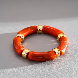 Detailed close-up showing orange marbled acrylic tubes and gold spacers on a chic bracelet