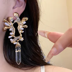 Dettaglio di orecchini vintage dorati con strass e pendente in cristallo trasparente