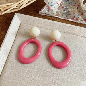 Close-up of summer style resin oval earrings with pink hoops and white beads