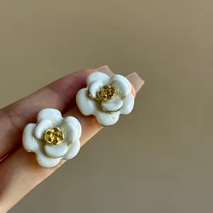 Detailed view of elegant creamy white enamel flower earrings with refined golden centers