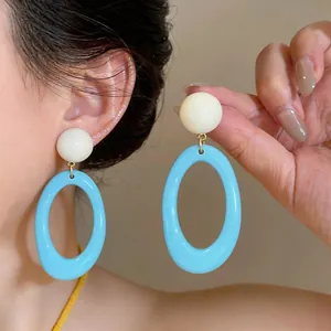 Close-up of dopamine blue and white resin oval dangle earrings for summer style
