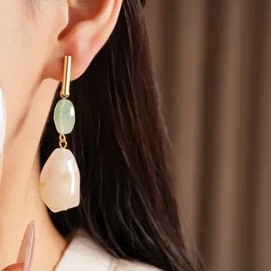 Primer plano de pendientes colgantes de resina jaspeada con detalle dorado