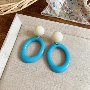 Close-up of summer dopamine resin oval earrings in bright blue and cream white