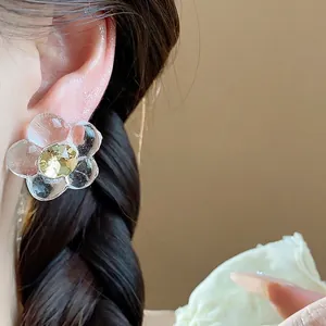 Elegant resin flower stud earrings with yellow crystal inlay shown on a model's ear