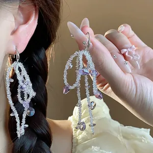 Elegant handmade glass beaded bow tassel earrings with purple crystals worn by model