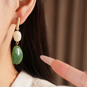 Primer plano detallado de elegantes pendientes geométricos de resina verde y blanca en la modelo