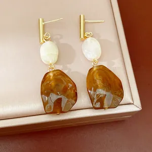 Primer plano de pendientes vintage de resina con perlas de color ámbar y blanco