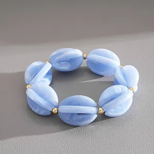 Close-up of blue swirled acrylic beads with gold spacers on an elastic bracelet.