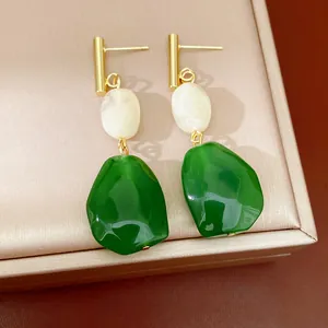 Detalle de pendientes retro de resina geométrica con cuentas blancas y piedras verdes