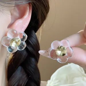 Close-up detail of stylish clear resin flower earrings with yellow faceted gem centers