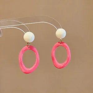 Detailed view of pink translucent resin oval earrings with white spherical studs