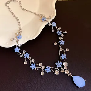 Close-up of elegant necklace featuring blue resin flowers and a water drop pendant