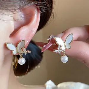 Elegant 14k gold plated butterfly stud earrings with zircon and pearl details on model