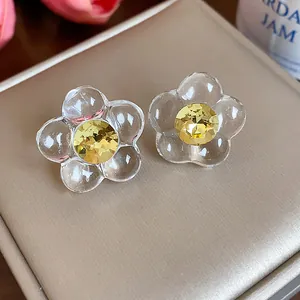 Close-up of elegant flower stud earrings with transparent resin petals and yellow crystal