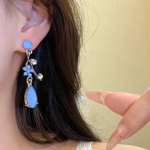 Macro detail of elegant light blue resin flower and waterdrop dangle earrings on ear