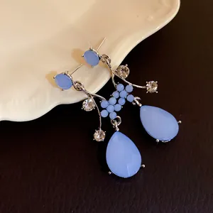 Macro detail of elegant light blue teardrop resin earrings with sparkling crystal accents