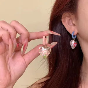 Close-up detail of sweet asymmetric heart earrings in a colorful dopamine style