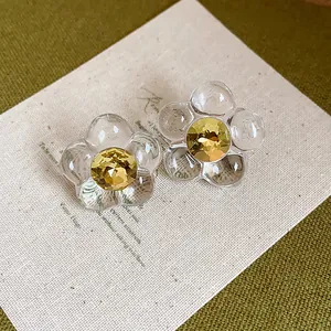 Close-up of elegant clear resin flower earrings with sparkling yellow crystals