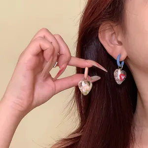 Close-up shot of asymmetric heart earrings featuring colorful dopamine resin charms