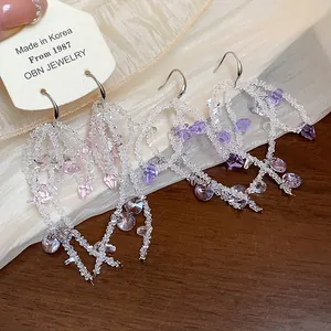 Detailed macro view of handmade glass beaded tassel earrings with purple crystals