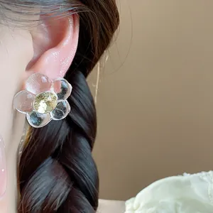 Detail shot of a transparent resin flower earring with a yellow crystal center.