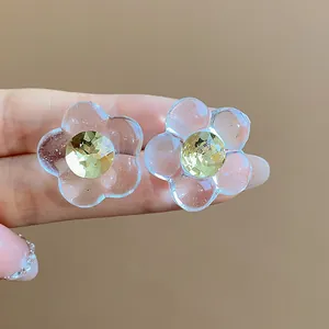 Close-up of resin flower stud earrings with a sparkling yellow rhinestone center