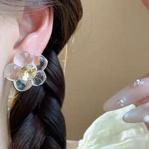 Close-up of a resin flower stud earring with diamond center in a minimalist style