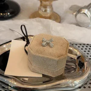 Detailed macro view of a silver zircon bow ear clip on a luxury velvet jewelry box.