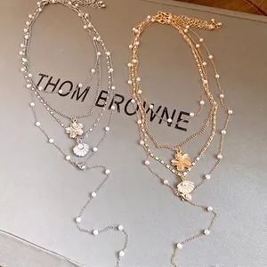 Elegant multi-layer pearl beaded necklace featuring chic shell and flower pendants.