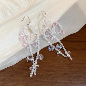 Detailed view of elegant glass beaded earrings with delicate pink bow and long tassels.