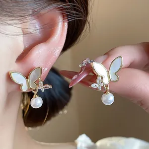 Detailed close-up view of gold plated butterfly earrings with zircons and pearls