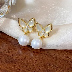 Macro detail of 14k gold plated butterfly stud earrings with pearls and zircon stones