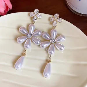Elegant silver needle zircon flower pearl drop earrings displayed on a cream plate.