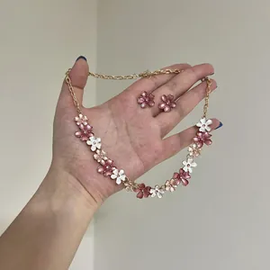 Nahaufnahme von elegantem rosa und weiß lackiertem Blumenhalskette und Ohrstecker Set