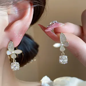 Close-up of 14k gold-plated butterfly earrings with zircons and square pendant