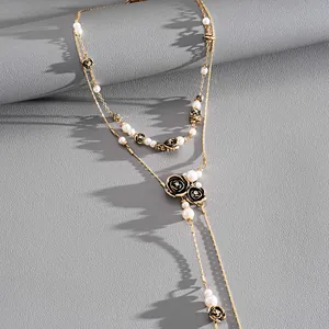 Détail du collier lariat vintage avec roses noires et perles sur chaîne dorée.